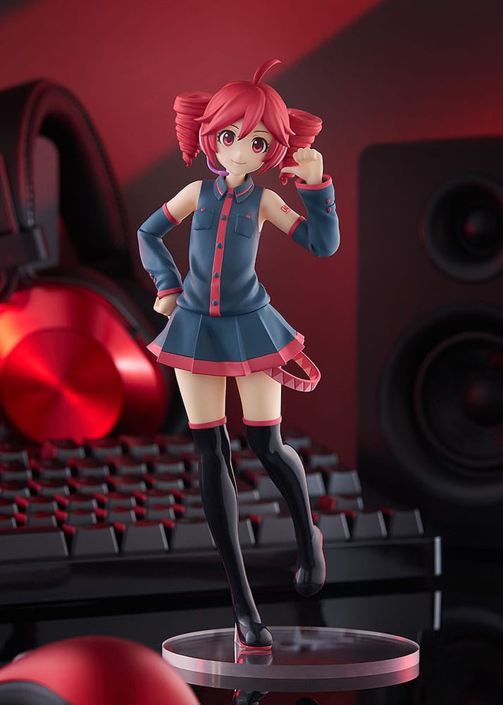 Figurine of a character with red hair and blue outfit in front of gaming equipment