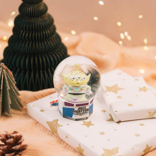 Snow globe with a character inside on a decorative surface with lights and paper trees.