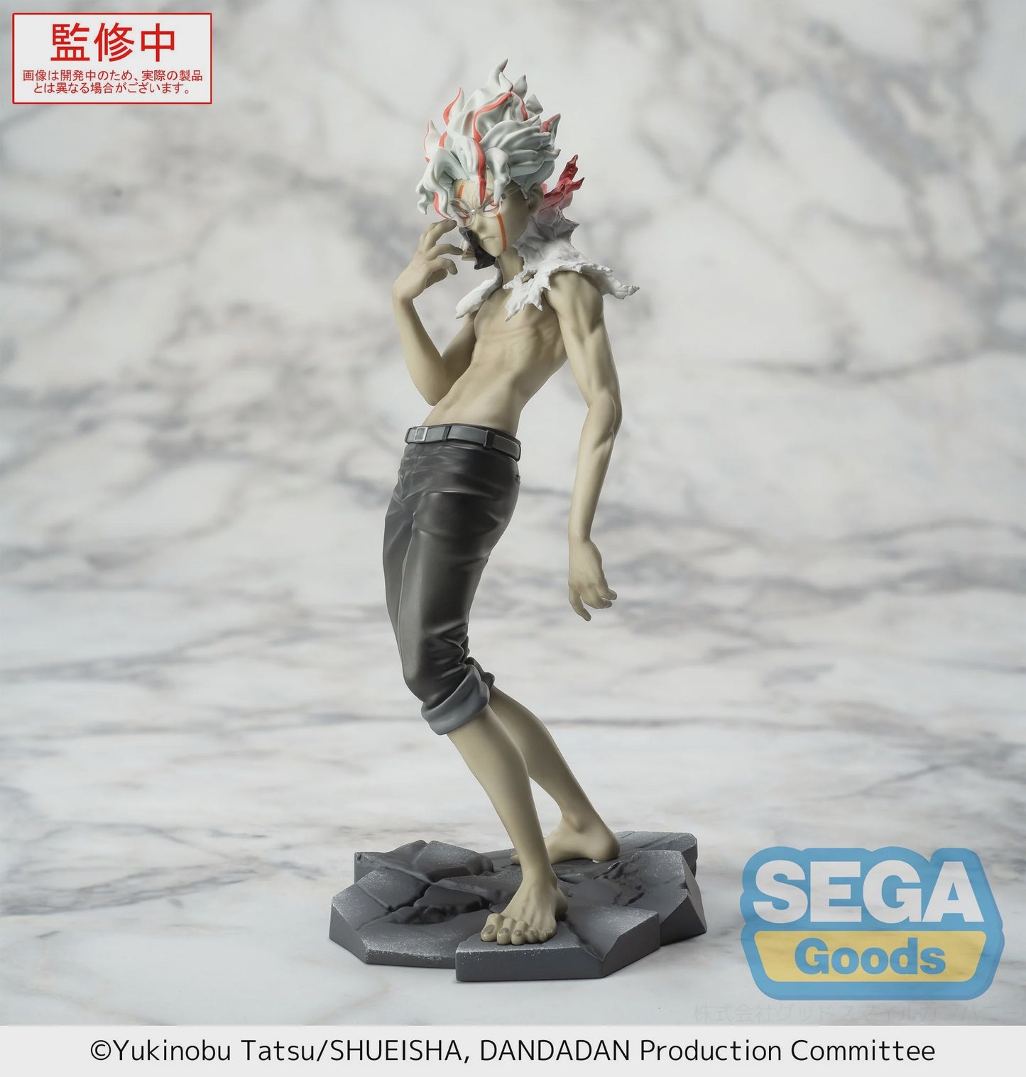 Figurine of a character with distinctive hair and clothing on a gray background, featuring the Sega Goods logo.