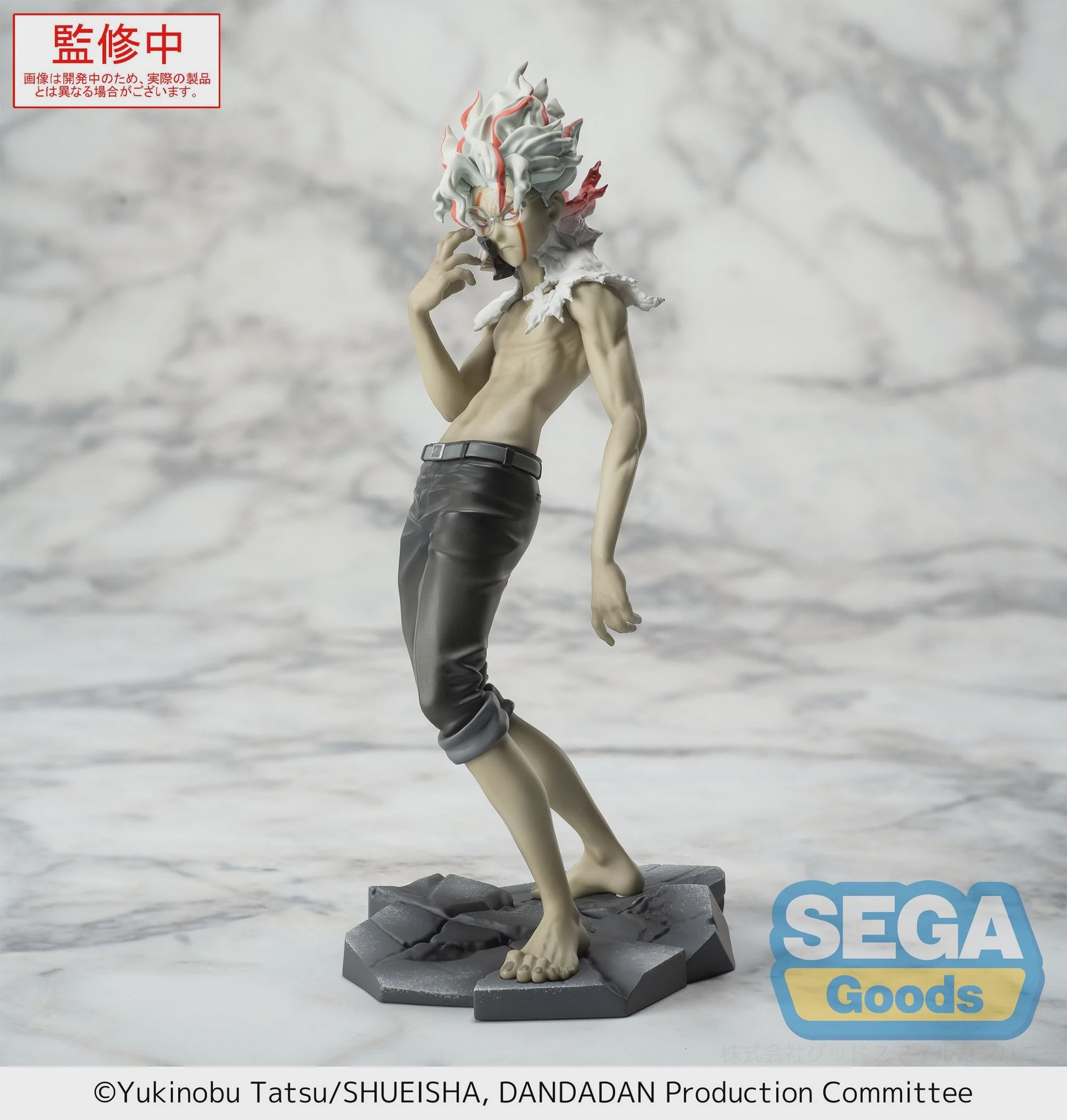 Figurine of a character with distinctive hair and clothing on a gray background, featuring the Sega Goods logo.