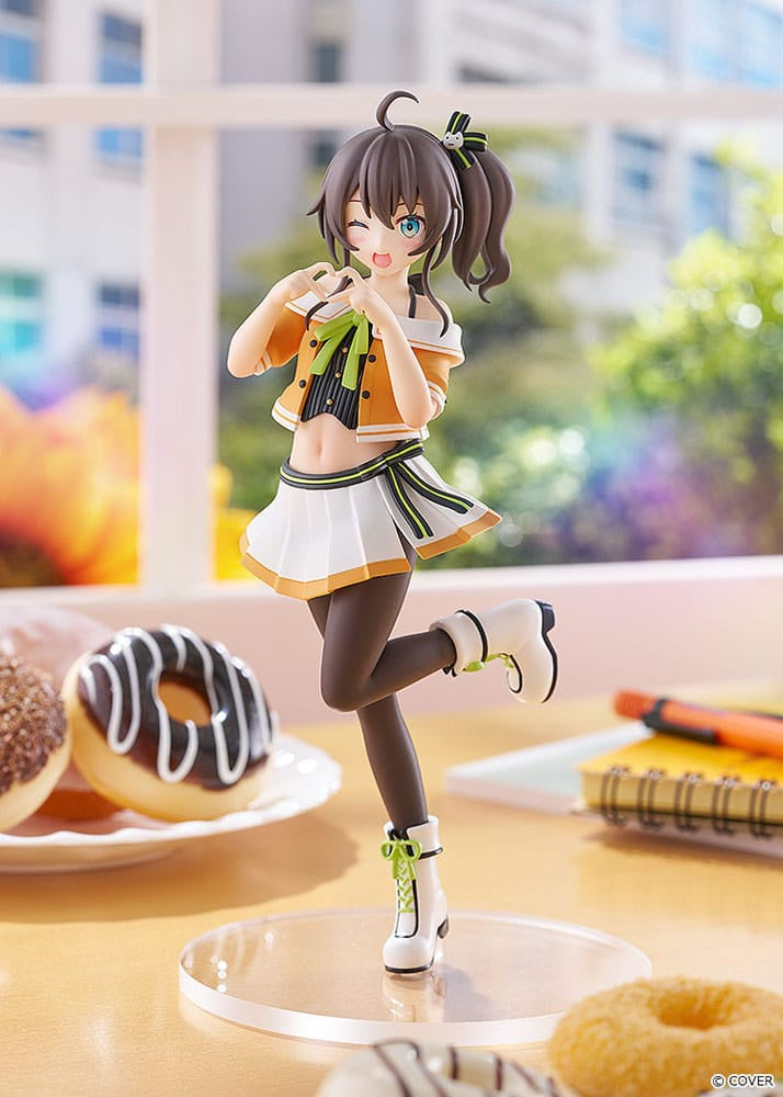 Figurine of a character in an orange and white outfit on a table with donuts and stationery.