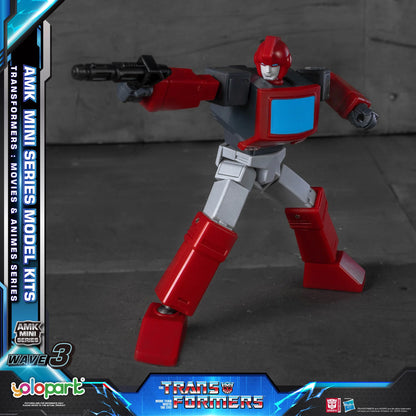 A red, gray, and white Transformers mini-series model kit figure posed dynamically with a black weapon, set against a dark gray studio backdrop. The image includes promotional graphic overlays for 'YoloPark' and 'Transformers'.
