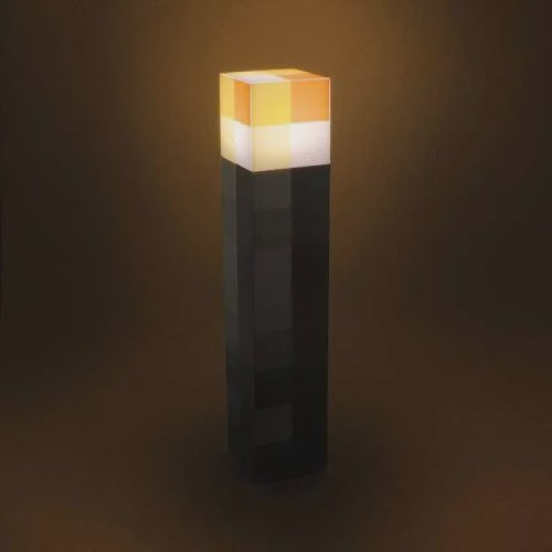 A plastic Minecraft torch light with a black body and an orange and white top, resembling the in-game torch design.