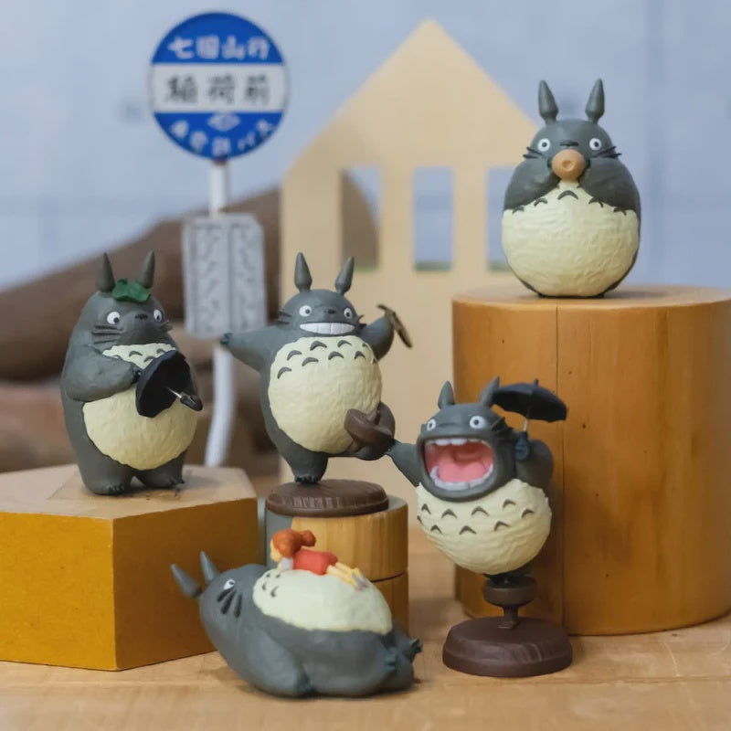 Collection of Totoro figurines on wooden stands with a blurred background