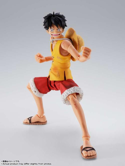 One Piece anime action figure of Luffy in a dynamic pose, wearing his signature yellow vest, red shorts with white trim, straw hat, and sandals, set against a light gray studio background.