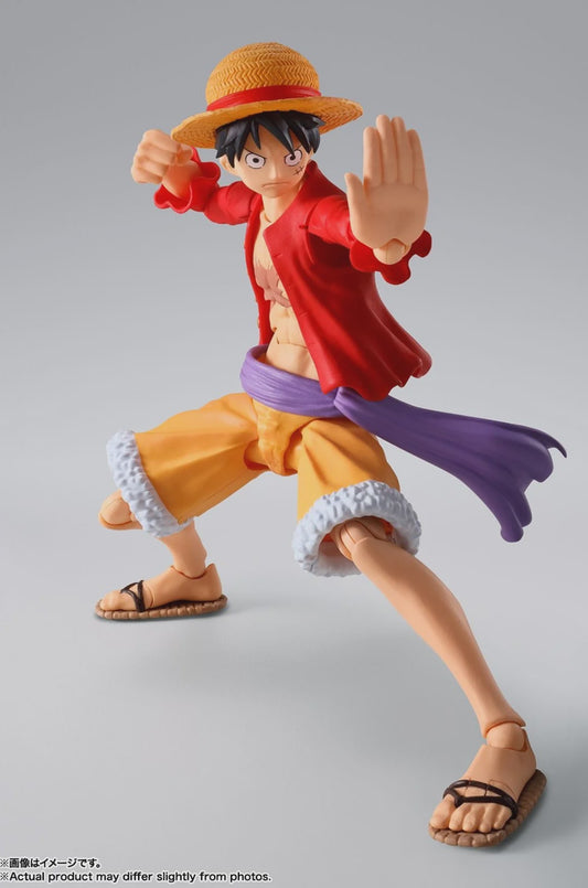 Action figure of a character in a red shirt and yellow pants with a straw hat on a gray background