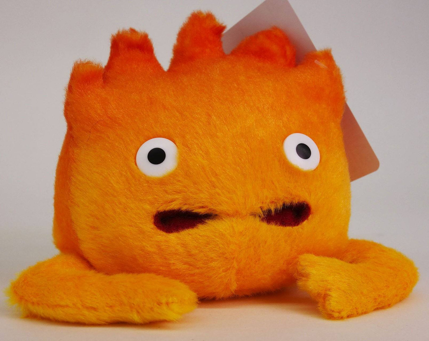 Orange plush toy with a sad expression on a white background